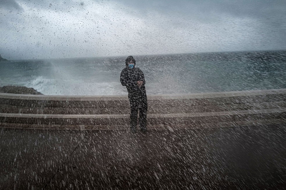 Homem é atingido por ondas durante tempestade na costa da França.  — Foto: Valery Hache/AFP