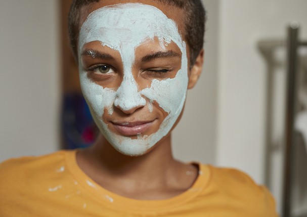 Close-up portrait of young woman with facial mask winking at home (Foto: Getty Images)