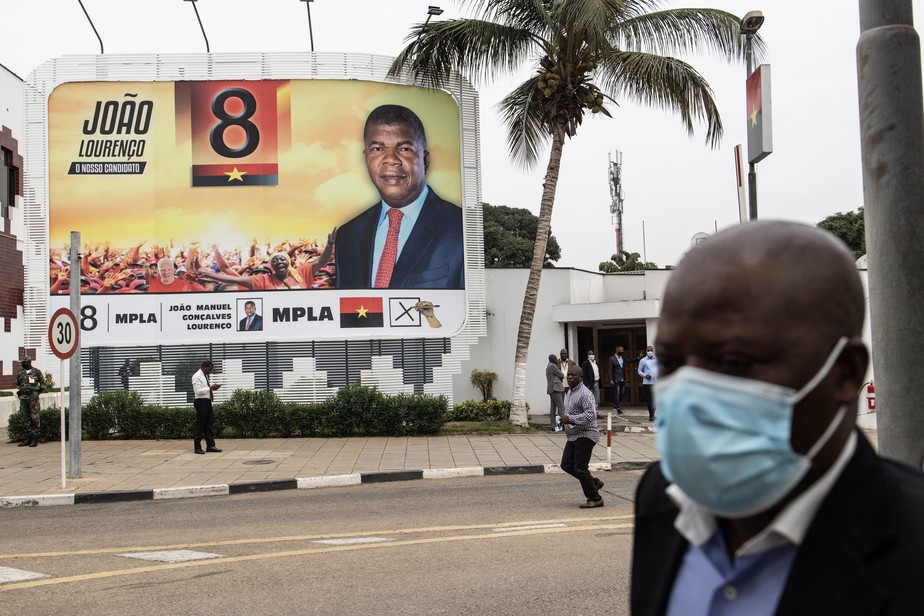 Pessoa passa diante de cartaz de campanha de João Lourenço, candidato da MPLA à Presidência de Angola