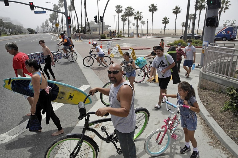 Grupo se aglomera antes de atravessar rua na praia de Huntington, nos EUA, neste domingo (26) — Foto: Marcio Jose Sanchez/AP Photo