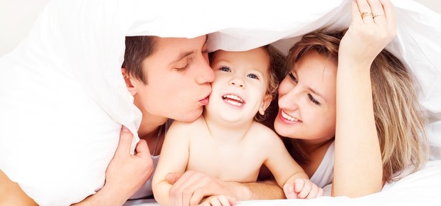 Criança na cama com os pais (Foto: Shutterstock)