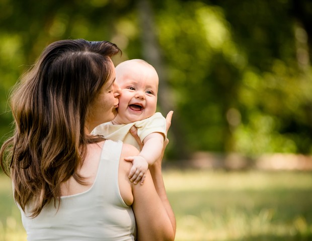 MÃ£e segura bebÃª no colo sorridente (Foto: Thinkstock)