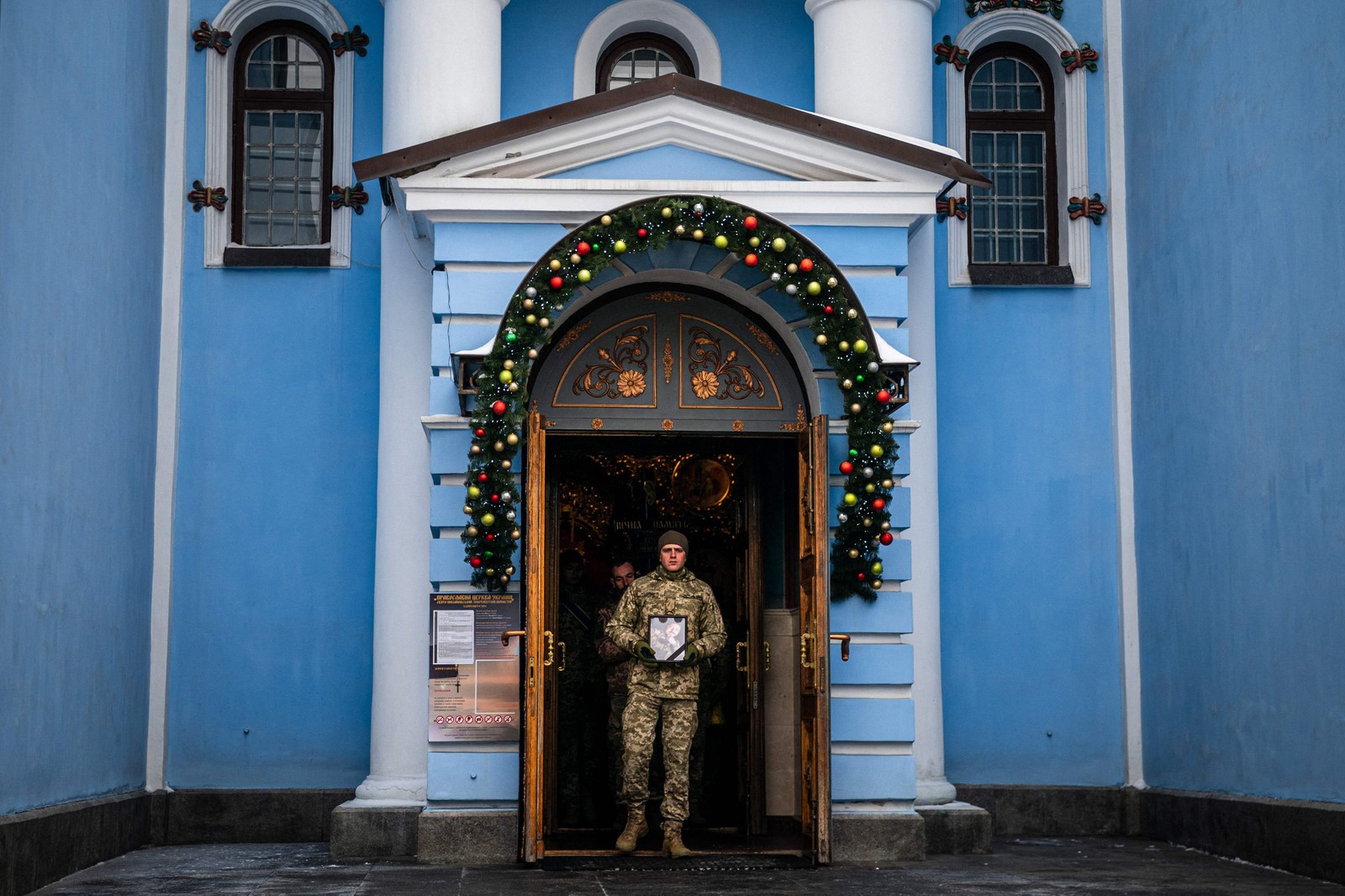 soldado carrega um retrato de Denys Galushko, um militar ucraniano morto enquanto lutava contra tropas russas na cidade de Bakhmut, durante seu funeral no Mosteiro Ortodoxo de São Miguel, em Kiev — Foto: Dimitar DILKOFF / AFP