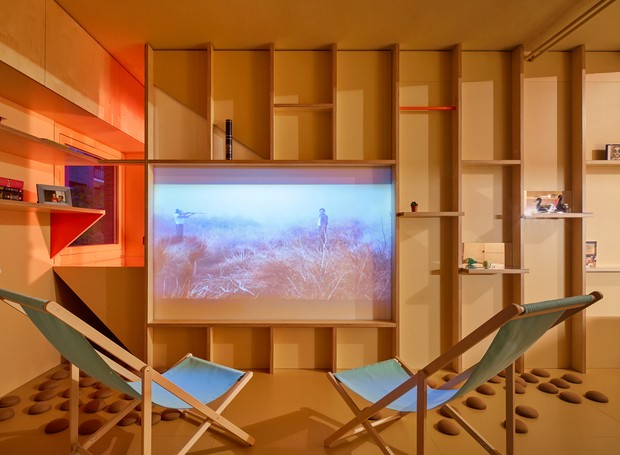 Na sala, há espaço para receber amigos. Com poucos móveis grandes, o local usa um telão como TV (Foto: José Hevia./ Dezeen)