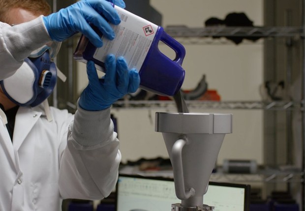 Um técnico despeja pó de metal em uma tremonha de uma impressora 3D de sinterização a laser usada pelo Relativity Space. (Foto: Divulgação)