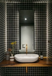 A arquiteta Kika Tiengo escolheu este banheiro como o único a ter os revestimentos substituídos. O ambiente ganhou pastilhas pretas em todas as suas faces, incluindo o teto