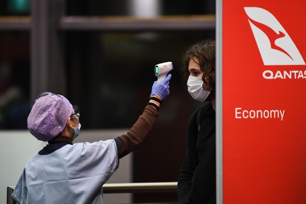 Agente do aeroporto mede a temperatura de um jovem passageiro em Sydney, na Austrália (Foto: Getty Images)