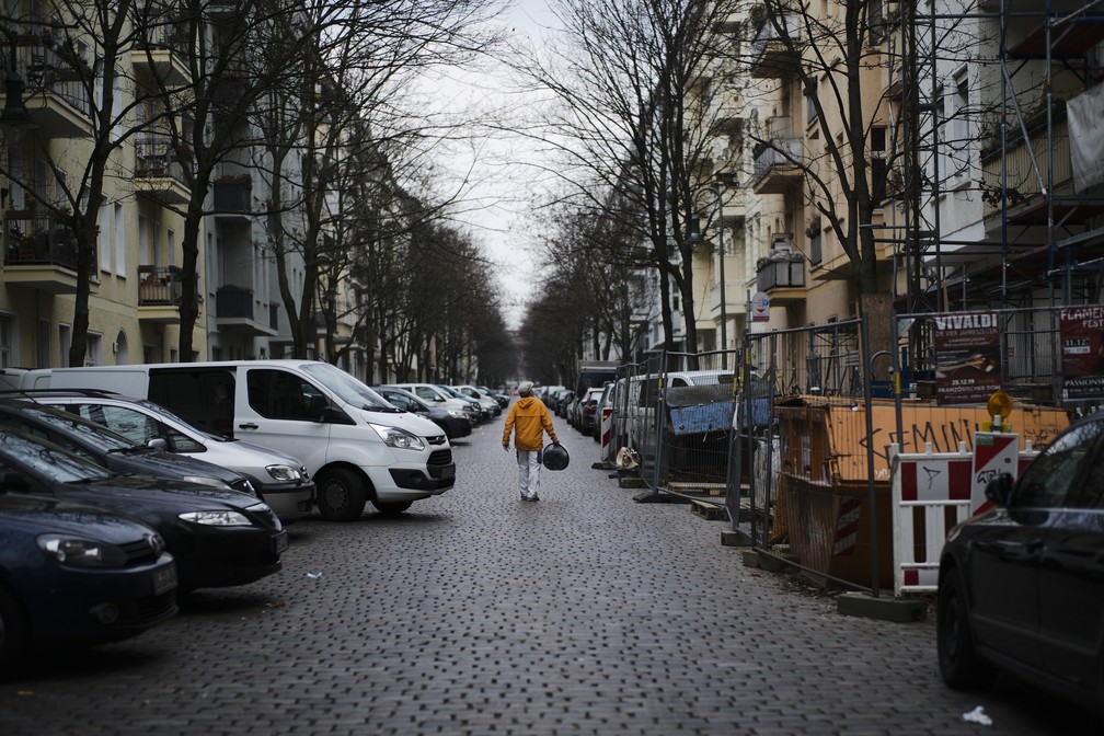 Um artesão solitário caminha sobre uma rua quase vazia no distrito Prenzlauer Berg, em Berlim, Alemanha, na terça-feira (17) — Foto: Markus Schreiber/AP