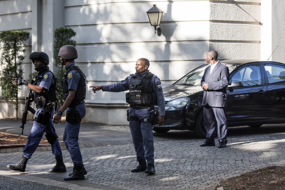 Policiais deixam casa de luxo da família Gupta após operação ligada a caso de corrupção na África do Sul  (Foto: Wikus de Wet/AFP)