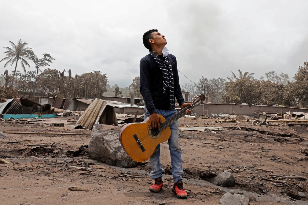 Brian Rivera carrega violão da irmã em San Miguel Los Lotes . O jovem perdeu 13 familiares na erupção do Vulcão do Fogo, na Guatemala (Foto: Reuters/Carlos Jasso)