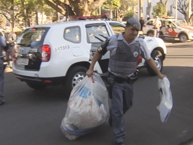 Policial chega com material recolhido de casas de suspeitos (Foto: Reprodução / TV TEM)