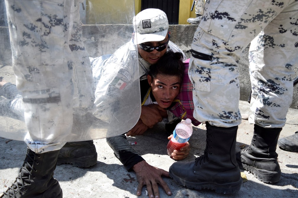Um membro da Guarda Nacional do México detém um migrante, parte de uma caravana que viaja para os EUA, perto da fronteira entre a Guatemala e o México, em Ciudad Hidalgo, no México, em 20 de janeiro  — Foto: Jose Torres/Reuters