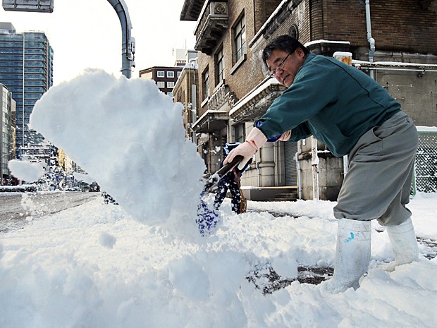 Homem remove neve em calçada de Nagoya, em Aichi, no centro do Japão nesta quinta-feira (18) (Foto: Jiji Press/AFP)