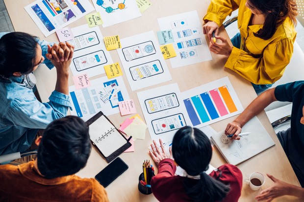 top view asian ux developer and ui designer brainstorming about mobile app interface wireframe design on table with customer brief and color code at modern office.Creative digital development agency (Foto: Getty Images/iStockphoto)