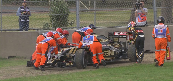 Após falha mecânica, Romain Grosjean ajuda fiscais a retirar Lotus da pista (Foto: Divulgação)