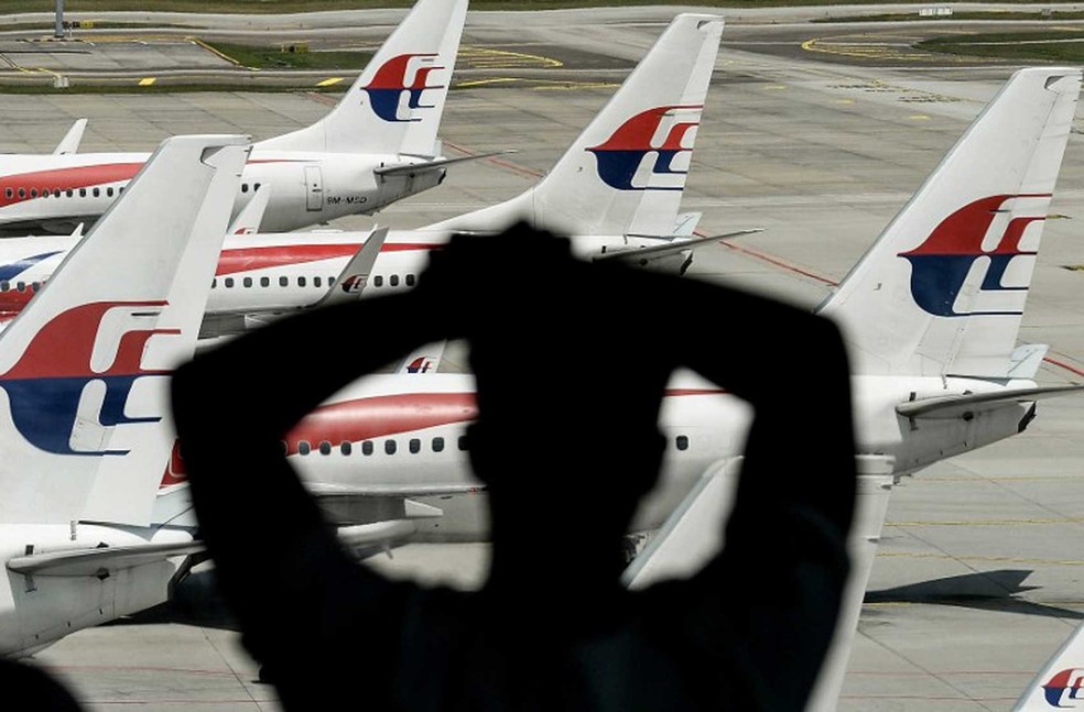 Homem olha aviÃµes da Malaysia Airlines parados no aeroporto de Kuala Lumpur, em imagem de arquivo (Foto: Manan Vatsyayana / AFP)