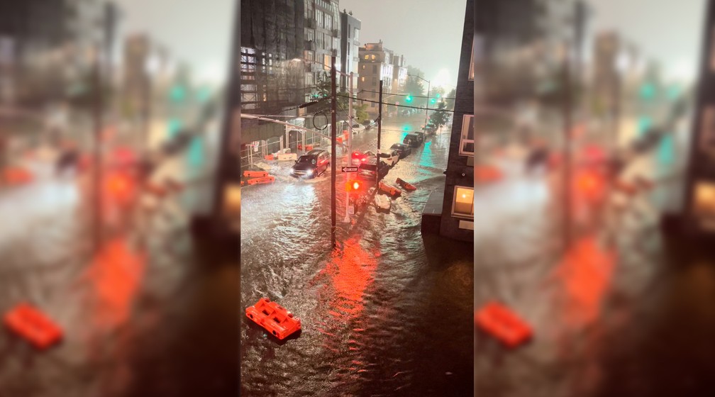 Veículo atravessa via alagada em meio a barreiras de segurança flutuando na enchente em Williamsburg, no bairro do Brooklyn, em Nova York, em 1º de setembro de 2021 nos Estados Unidos — Foto: Jaymee Sire via Reuters