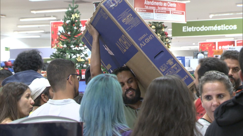 Homem carrega televisor comprado na Black Friday  — Foto: TV Globo/Reprodução/Arquivo