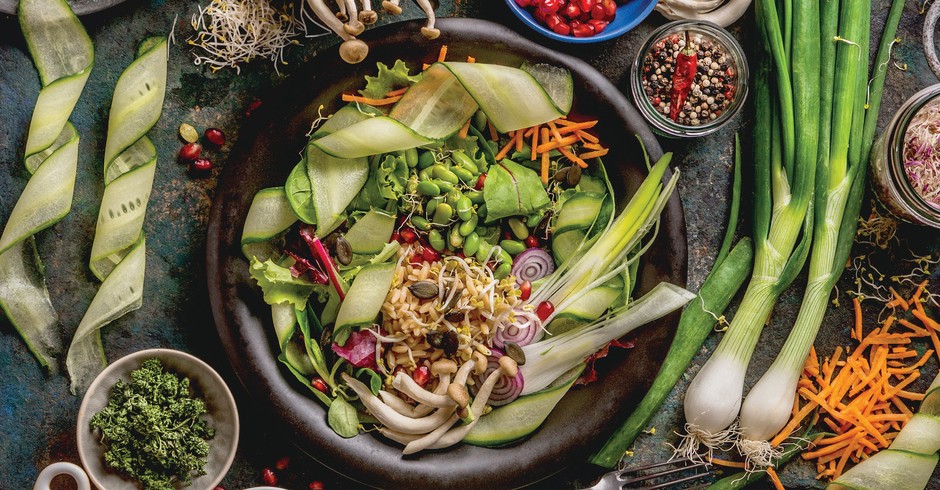 Healthy vegan lunch bowl making. Detox beautiful Buddha bowl with various fresh vegetables, edamame beans, mushrooms, seasoning and pumpkin seeds and nuts topping on rustic table with ingredients. Top view. Food flat lay (Foto: Getty Images)