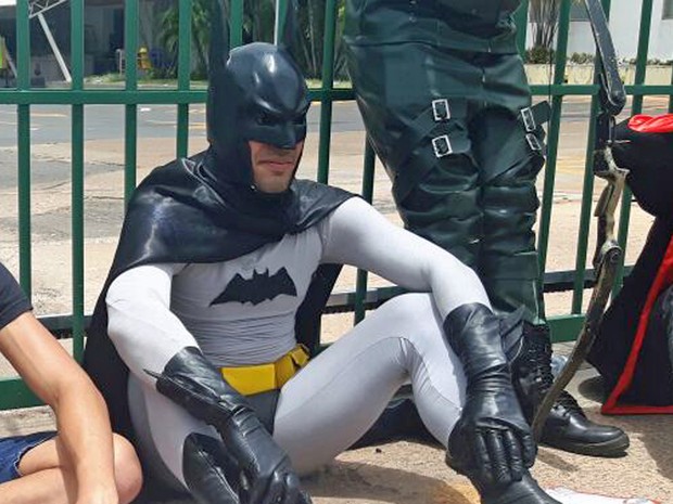 Rapaz vestido de Batman para Enem sentado ao lado de colegas &#39;justiceiros&#39; se apoiando em grade de local de prova (Foto: Fernanda Calgaro/G1)