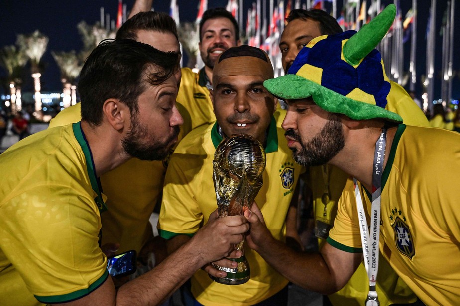 Grupo de torcedores do Brasil posa com uma réplica do troféu da Copa do Mundo no Flag Plaza, em Doha