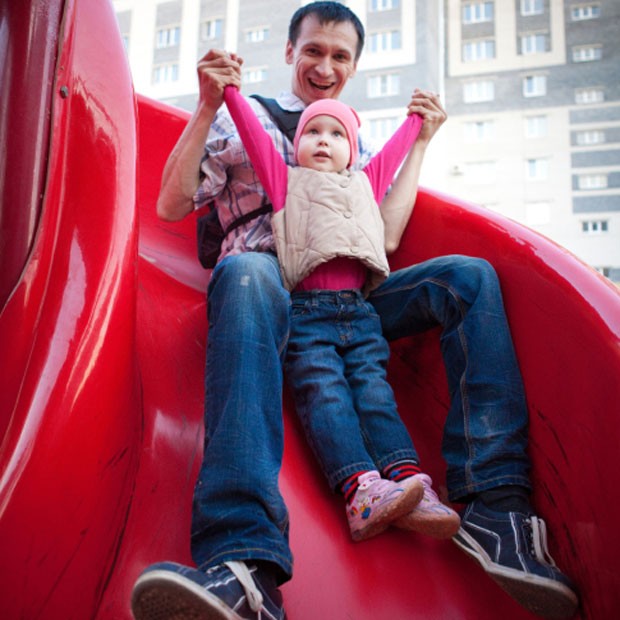 O pai escorrega com a criança no colo: brincadeira não é recomendada (Foto: Thinkstock)
