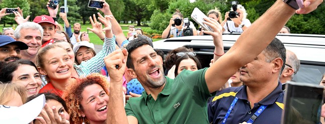 Tenista sérvio Novak Djokovic tira selfies com seus torcedores em Melbourne, depois de vencer o aberto da Austrália — Foto: SAEED KHAN/AFP