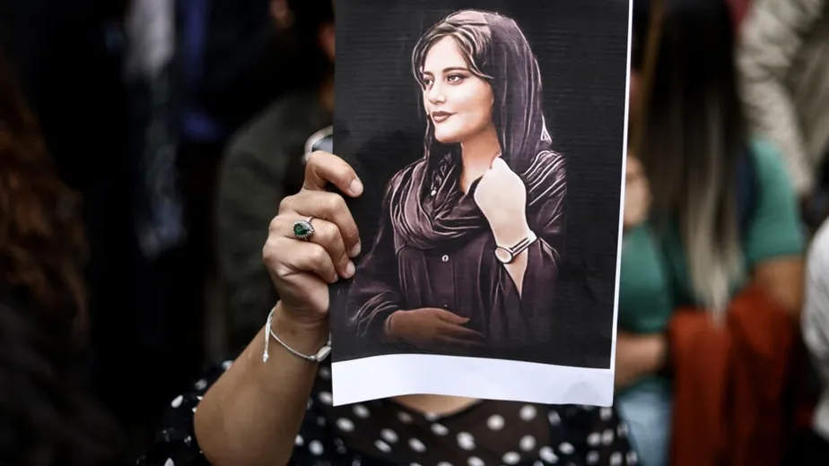 Uma manifestante segura um retrato de Mahsa Amini durante uma manifestação em seu apoio em frente à embaixada iraniana em Bruxelas