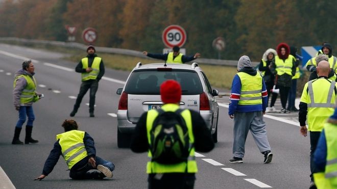 Um carro avança sobre um grupo de 'coletes amarelos', os manifestantes franceses que estão paralisando vias contra aumento do preço do diesel na França (Foto: Reuters/BBC)