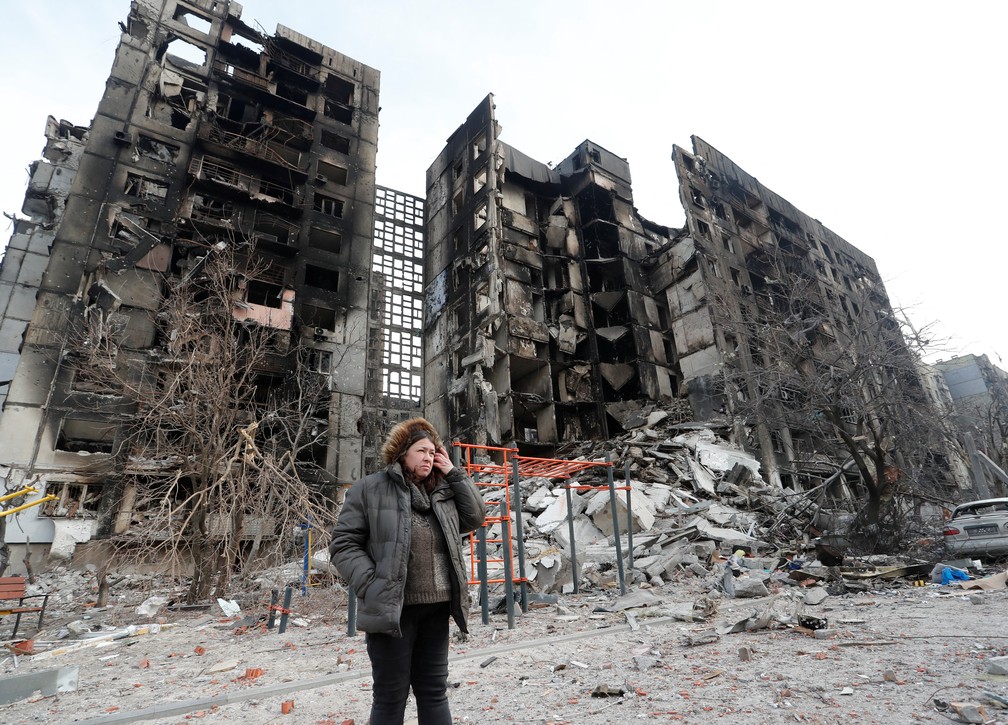 Svetlana Savchenko ao lado do prédio destruído onde seu apartamento estava localizado em Mariupol, em março — Foto: Reuters/Alexander Ermochenko