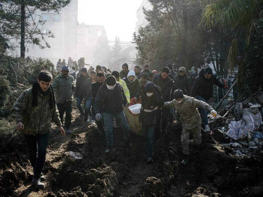 Pessoas carregam um corpo encontrado por equipes de resgate em um prédio desabado, em Kahramanmaras, Turquia