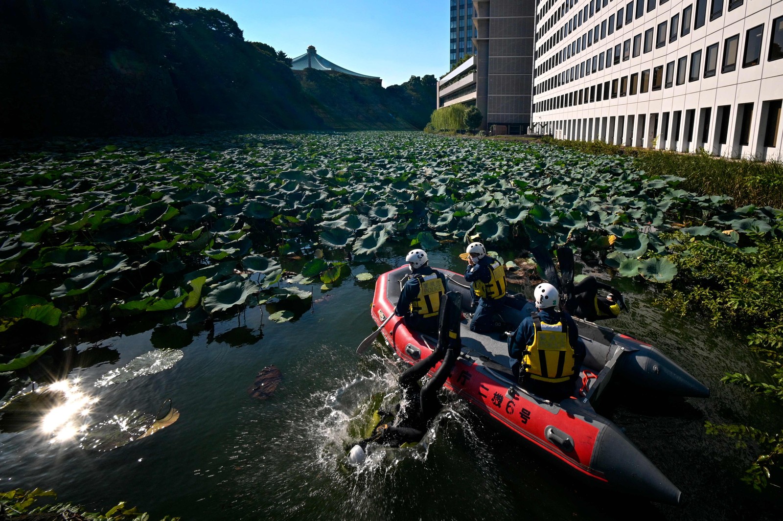 Equipe de resgate do Departamento de Polícia Metropolitana de Tóquio procura um fosso no Parque Kitanomaru em busca de objetos perigosos, em Tóquio — Foto: Kazuhiro NOGI / AFP