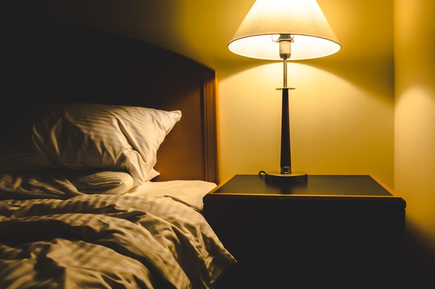 Closeup shot of messy bedroom with lamp near bad (Foto: Getty Images/iStockphoto)
