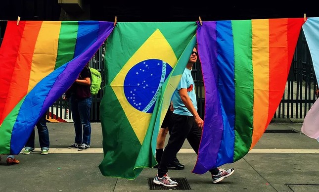 Pedestre vê bandeiras do Brasil e da luta LGBTQIA+, 
