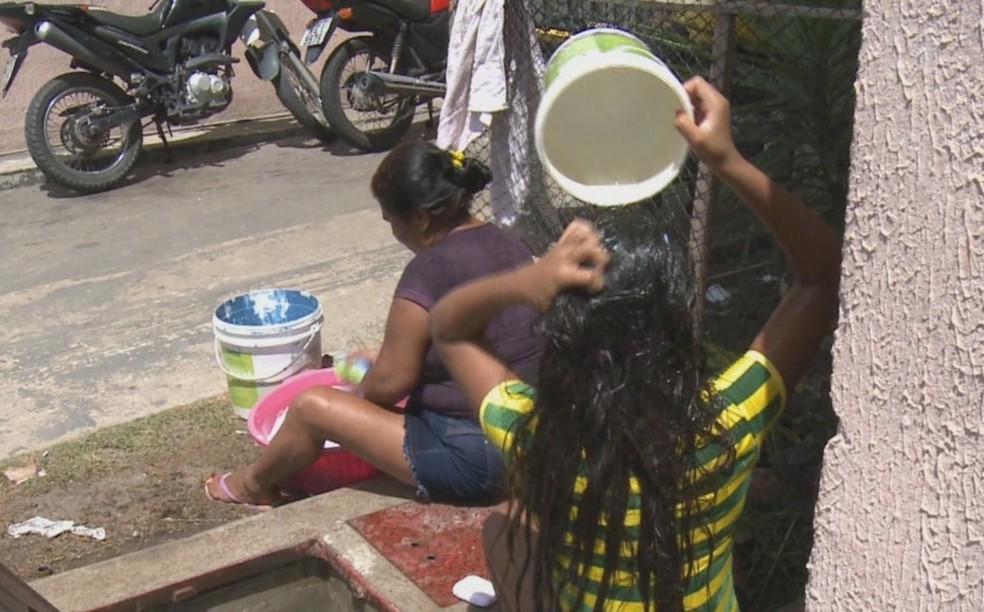 Sem água, mãe e filha tomam banho e lavam roupa usando baldes em Macapá — Foto: Rede Amazônica/Reprodução