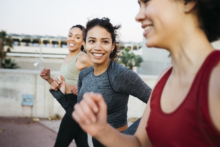 Three smiling young women in sportswear jogging in an urban setting (Photo: Getty Images)