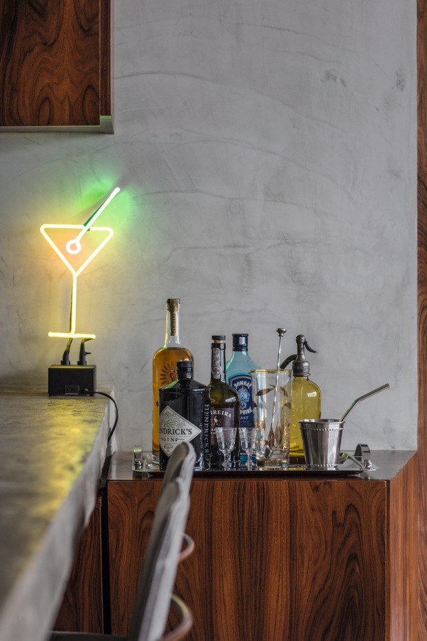 Bar. Em um canto da cozinha, um móvel de pau-ferro abriga garrafas de bebidas junto de uma luminária de néon (Foto: André Klotz / Editora Globo)