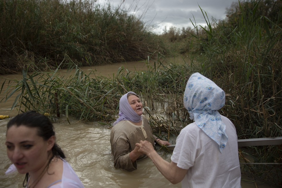Peregrinos cristãos entram nas águas do Rio Jordão durante uma cerimônia de batismo que faz parte da Festa da Epifania Ortodoxa, no local de batismo Qasr al-Yahud, próximo à cidade de Jericó, na Cisjordânia — Foto: Oded Balilty/AP