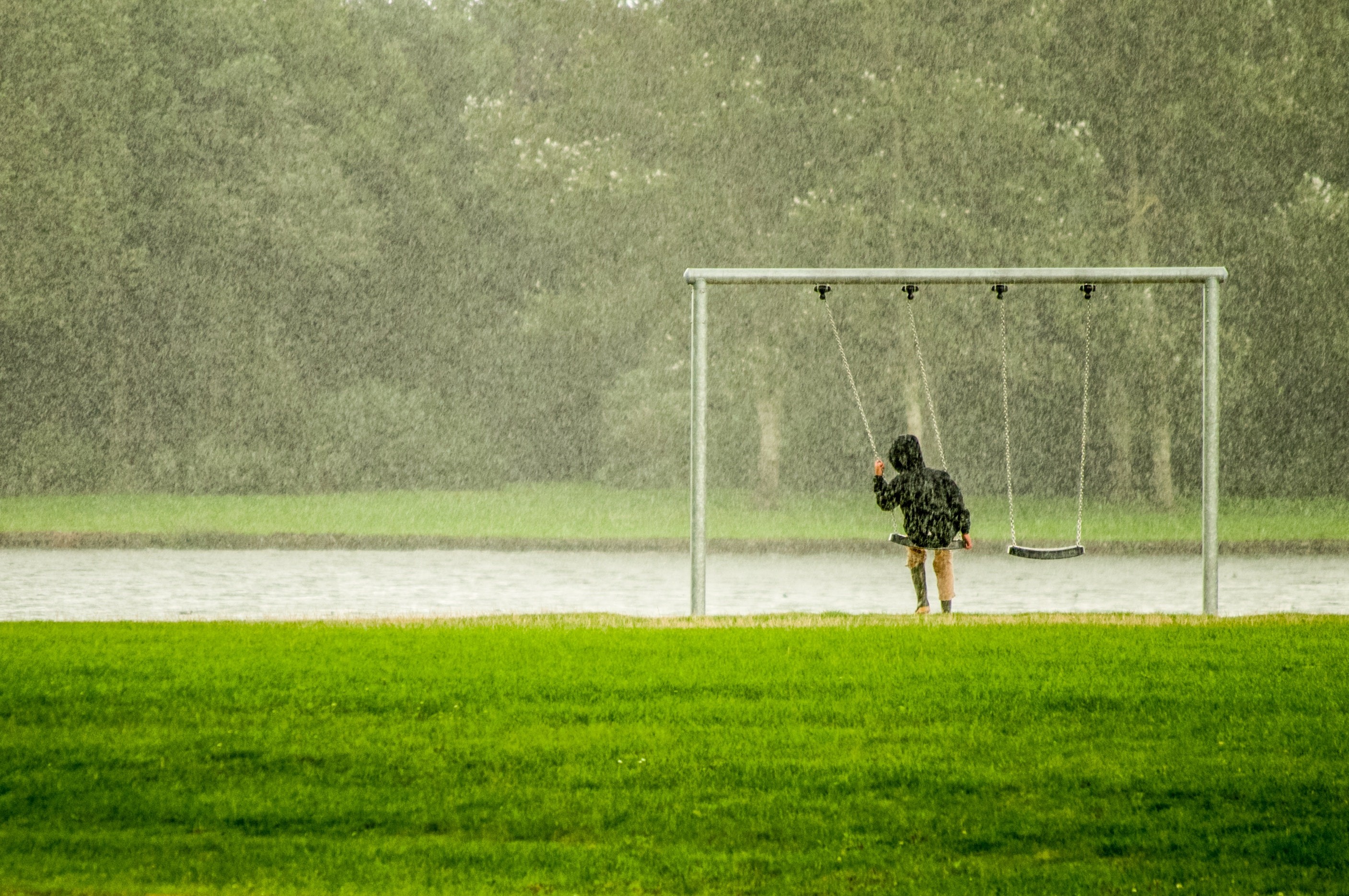 Criança toma chuva no parque enquanto brinca no balanço (Foto: Skitterphoto/Pexels)