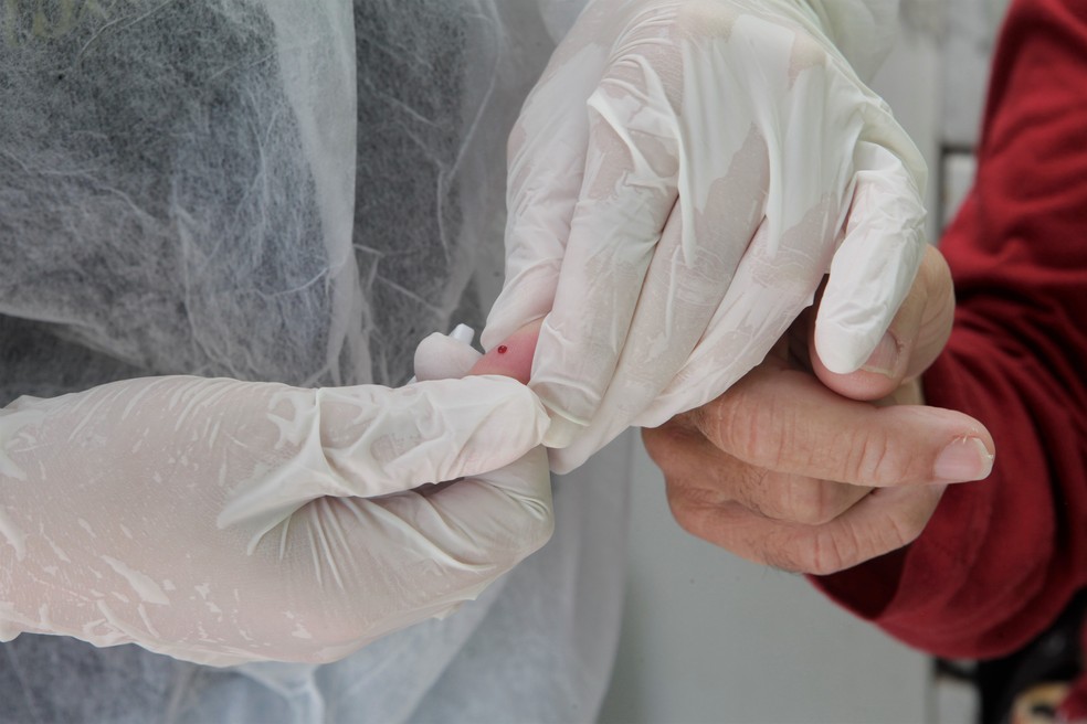 Pesquisadores retiram uma gota de sangue para identificar anticorpos — Foto: Daniela Xu/UFPel