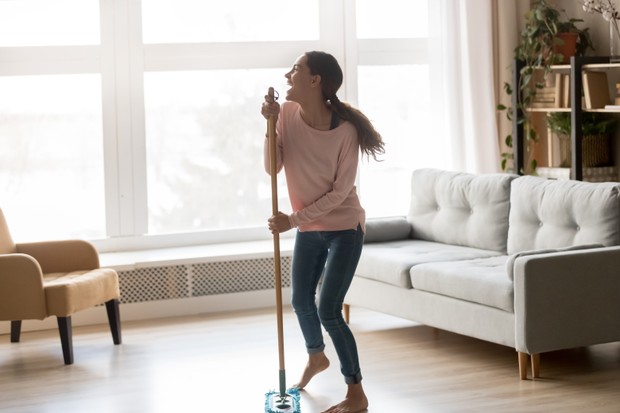 Barefoot happy young multiracial girl having fun during living room cleaning, using microfiber wet mop pad as microphone stand, dancing and singing, enjoying cleaning homework routine. (Foto: Getty Images/iStockphoto)