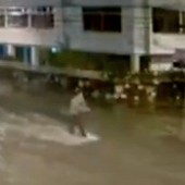 Jovem surfa em rua alagada após chuva (Reprodução/TV Globo)