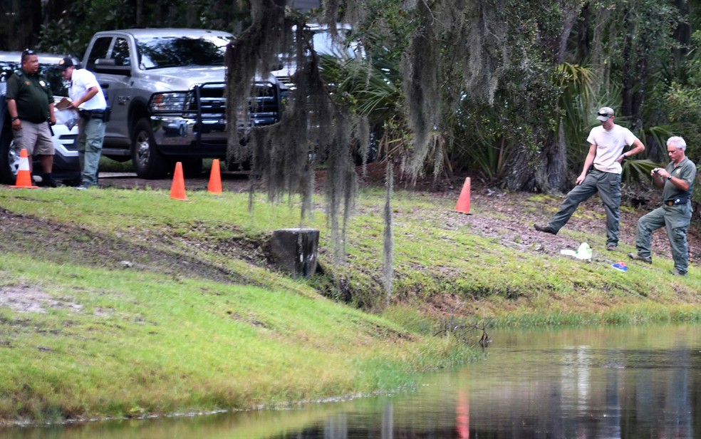 Policiais e funcionários do Departamento de Recursos Naturais da Carolina do Sul fotografam local onde Cassandra Cline foi arrastada para dentro de um lago e morta por um alligator na segunda-feira (20), em Hilton Head Island (Foto: Drew Martin/The Island Packet via AP)