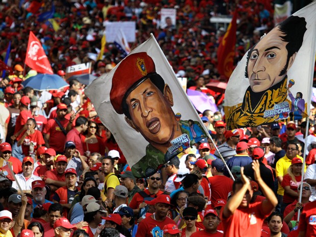 Nesta foto de 10 de janeiro, militantes do presidente da Venezuela Hugo Chávez carregam bandeiras com o desenho do presidente com vestimentas militares e com a imagem de Simon Bolivar durante a posse simbólica de Chávez, em Caracas (Foto: AP Photo/Fernando Llano, File)