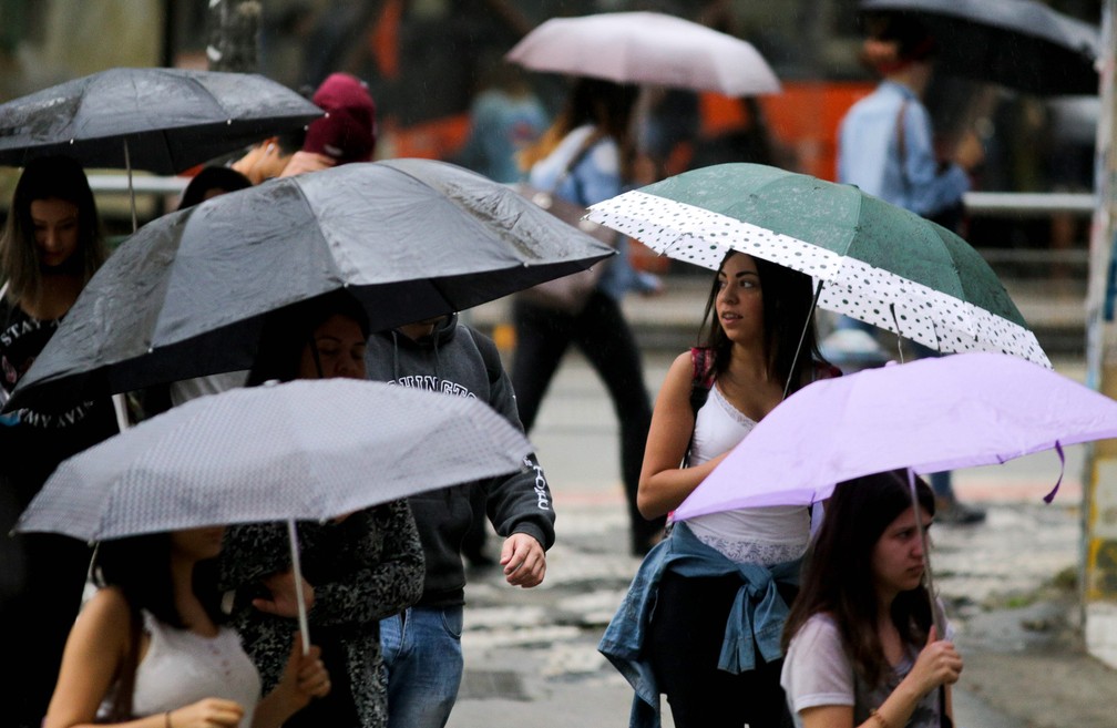 Pedestres se protegem da chuva na manhã desta sexta-feira (17) em São Paulo (Foto: Dario Oliveira/Estadão Conteúdo)