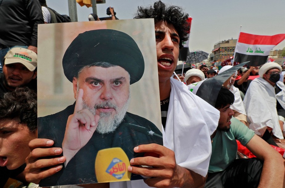 Um apoiador do clérigo xiita iraquiano Muqtada al-Sadr levanta um cartaz que o retrata durante uma oração coletiva de sexta-feira na cidade de Sadr