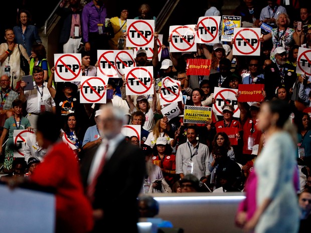 Delegados seguram cartazes contra o Tratado de Livre Comércio Trans-Pacífico (TPP, na sigla em inglês) no Wells Fargo Center, onde teve início nesta segunda a convenção do Partido Democrata (Foto: Aaron P. Bernstein/Getty Images/AFP)