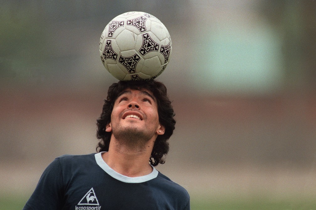 O astro do futebol argentino Diego Maradona equilibra uma bola ao sair do campo após treino em 22 de maio de 1986, na Cidade do México — Foto: Jorge Duran/AFP