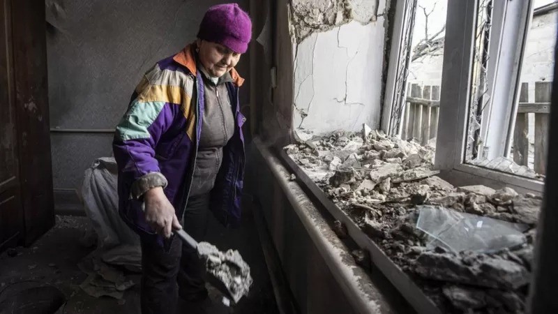 Mulher limpa a casa danificada após ataque de artilharia de uma área de Donetsk, sob o controle de rebeldes apoiados pela Rússia (Foto: Anadolu Agency via Getty Images)