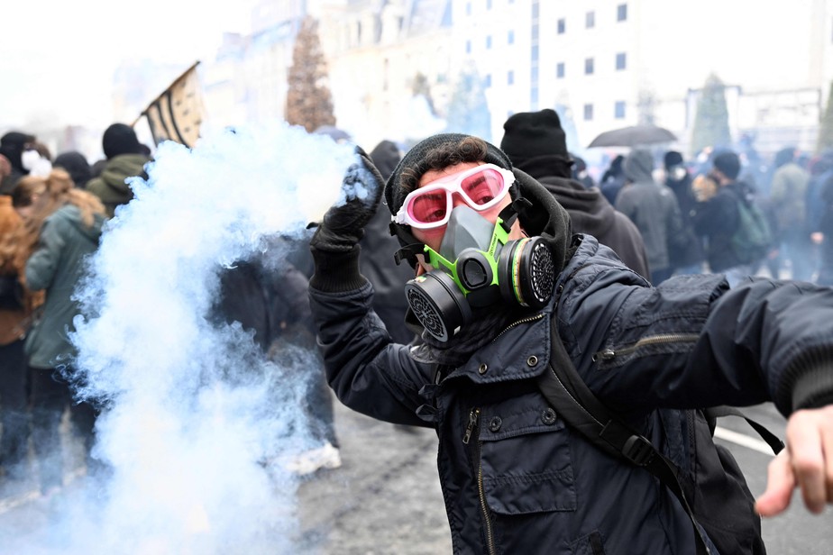 Manifestante joga uma granada de gás lacrimogêneo contra a polícia de choque durante uma manifestação em Rennes, oeste da França